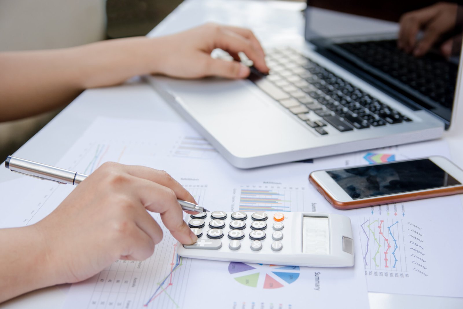 Life Settlement - Life Settlement Calculator - close up woman using calculator and laptop on paper graph data with doing work at office. SELL YOUR POLICY