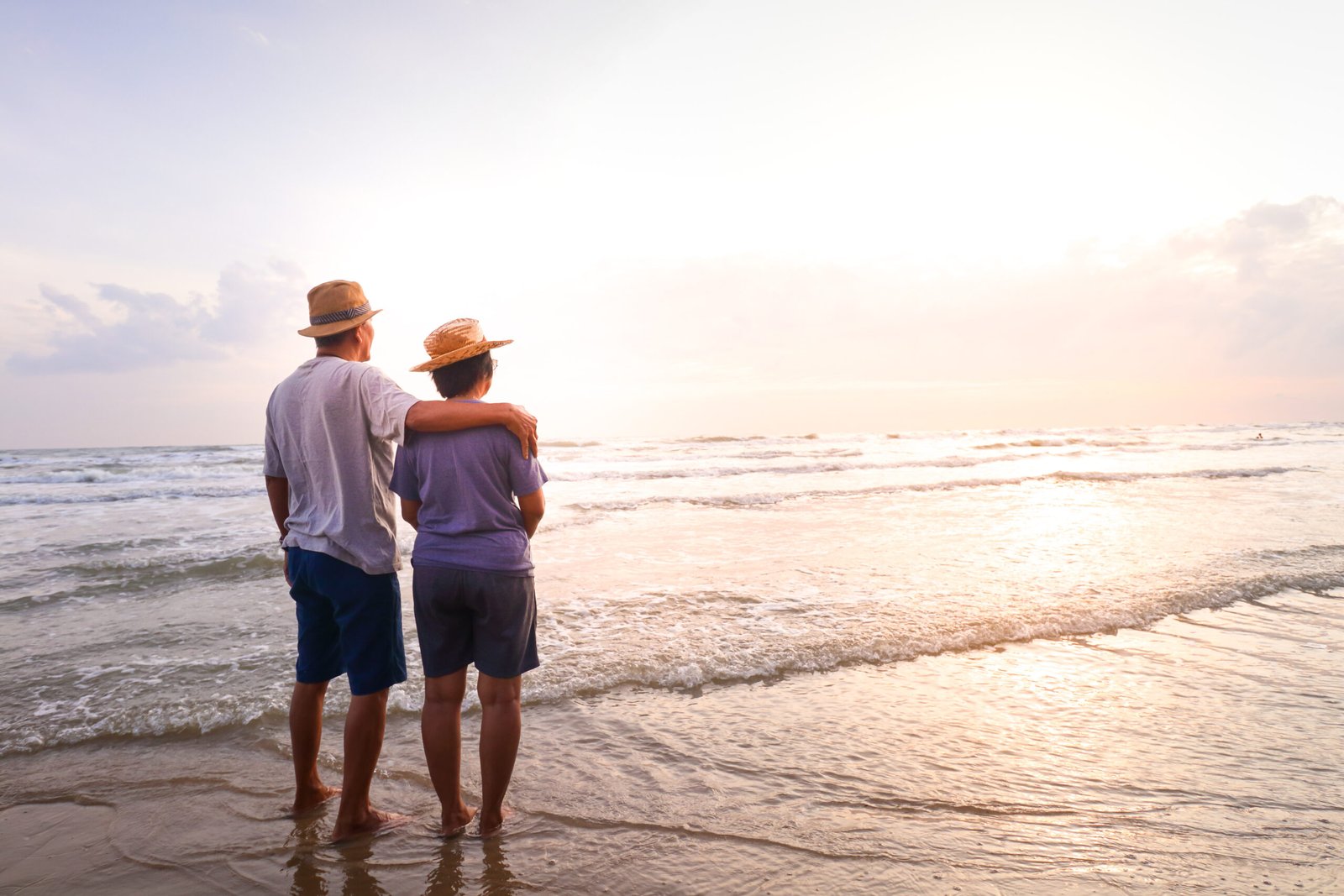 Life Settleement - An elderly Asian couple Stand together on the beach Look at the beautiful sea in the morning together. Travel concept to live happily in retirement age. life insurance policy term