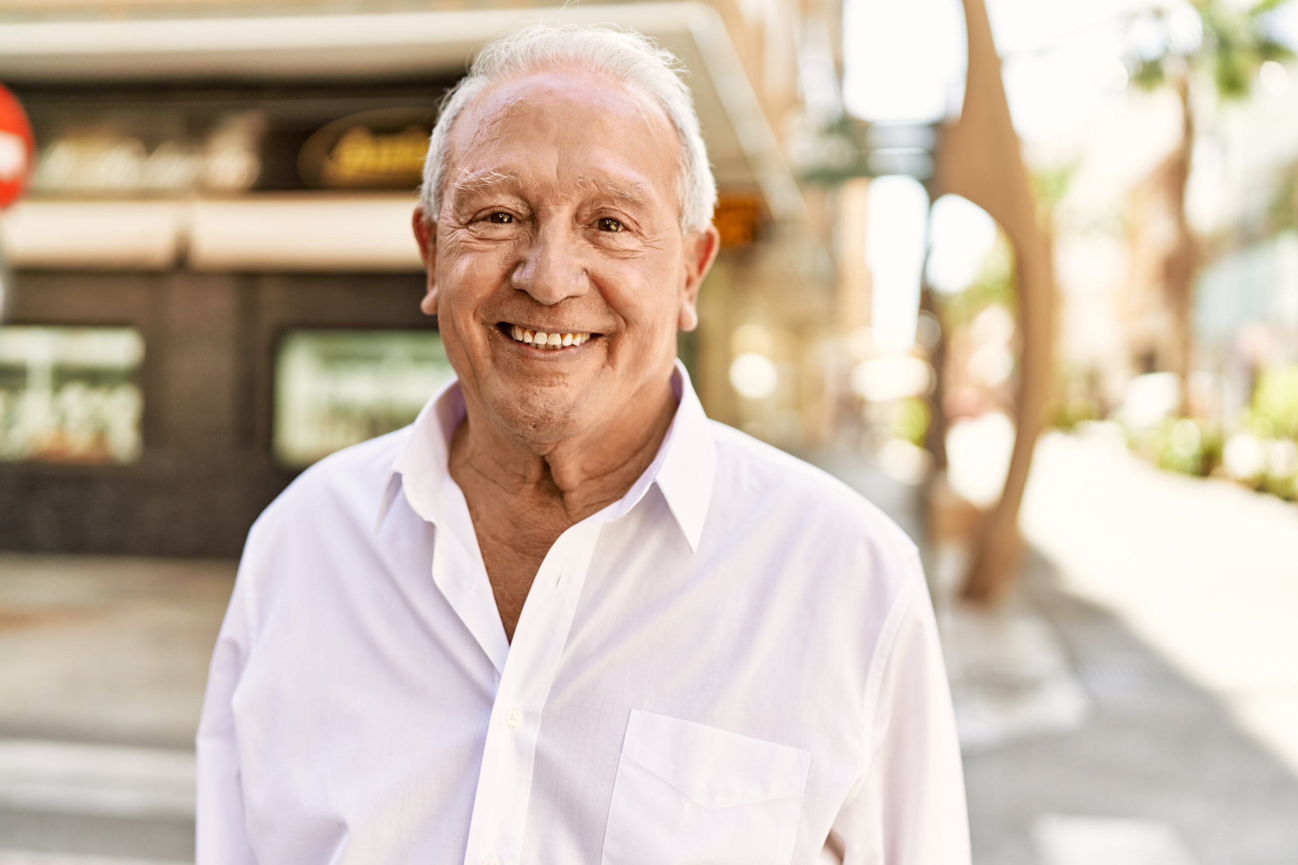 Life Settlement - Senior man with grey hair standing happy outdoors on a sunny day.