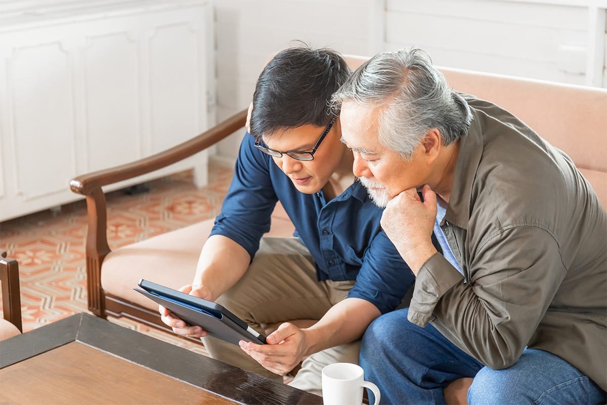 Life Settlement - a son showing his senior Father something on an Ipad. CHOOSING RETAINED DEATH BENEFIT