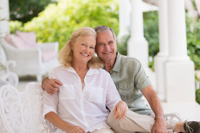 Portrait happy senior couple hugging on patio Life Settlement Sevices - Portrait happy senior couple hugging on patio. LIFE SETTLEMENTS