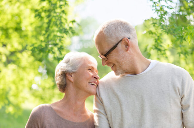 life settlement – happy senior couple over green natural background Life Settlements - Happy senior couple smiling outdoors.