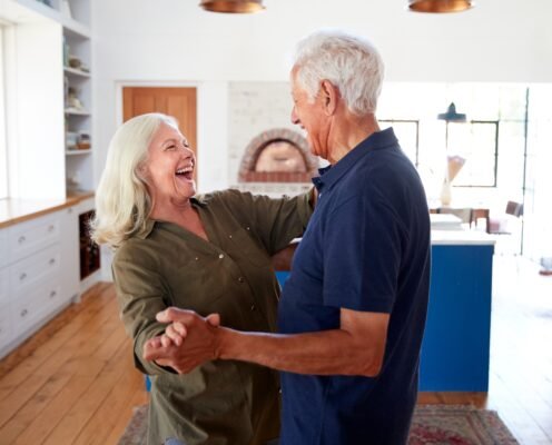 Life Settlements: Learn About the Pros and Cons Now: Senior Couple At Home Dancing In Kitchen Together