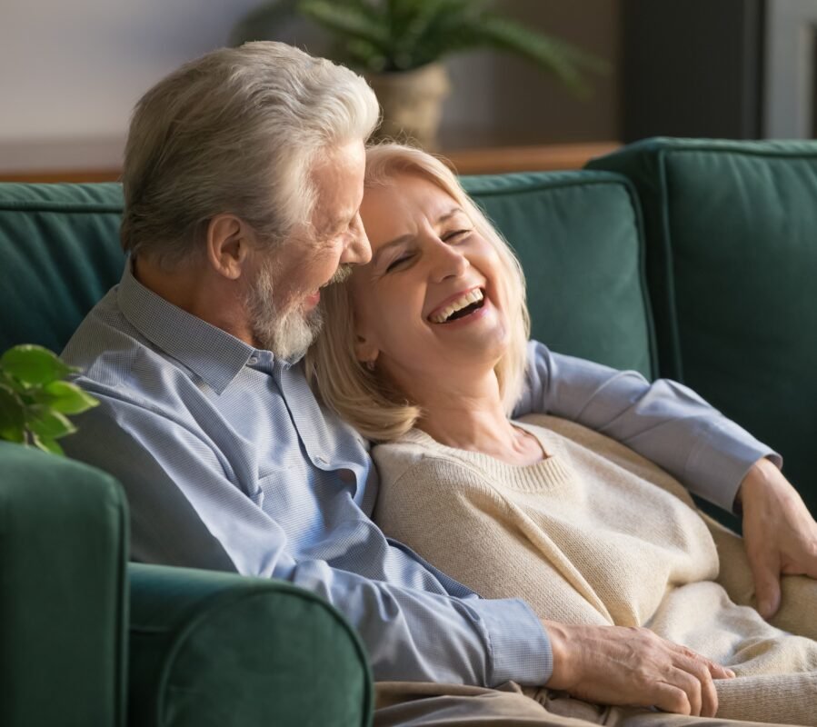 Life Settlements: a man and woman sitting on a couch laughing