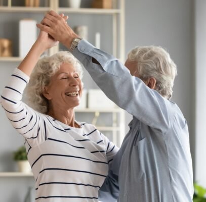 Life Settlement Broker - Overjoyed mature husband and wife dance in living room