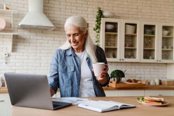 Life Settlement Taxes - a woman holding a cup and looking at a laptop