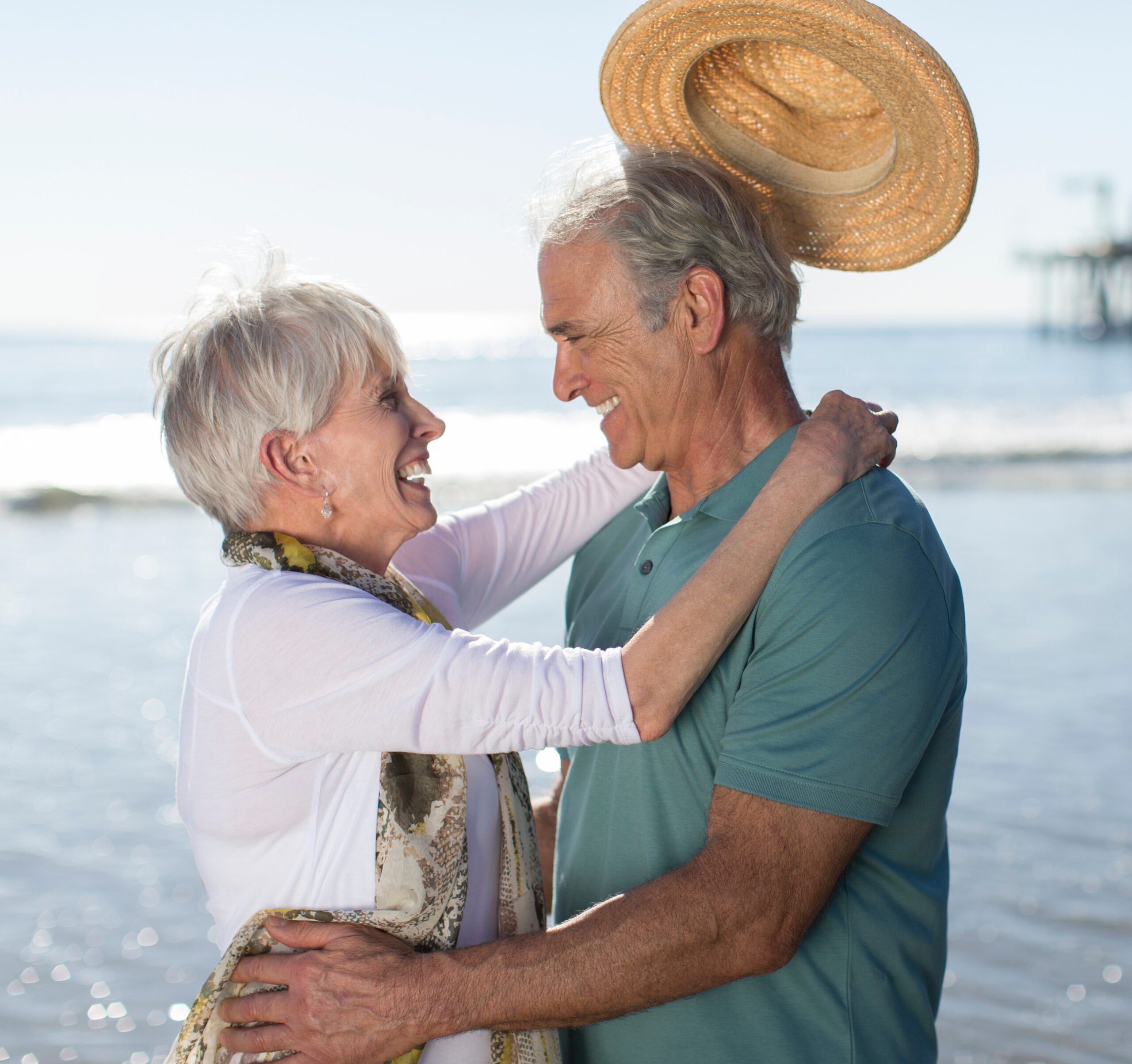 Viatical Settlement - happy senior couple smiling while embracing on the beach