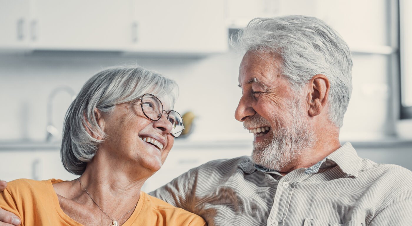 Life Insurance Cash Surrender Value - Happy mature husband and wife sit rest on couch at home hugging and cuddling, show care affection, smiling senior loving couple relax on sofa have fun, enjoy tender romantic family weekend together.