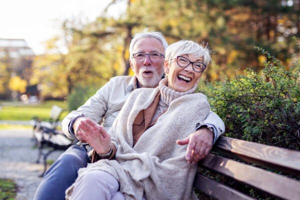 Selling a term life insurance policy: senior couple sitting on bench and smile