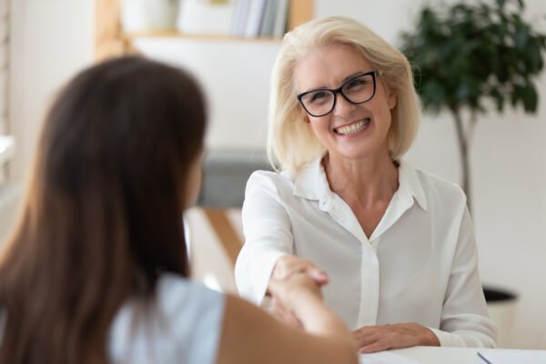 Companies that buy life insurance policies: Smiling middle-aged woman shakes hand after successful negotiation