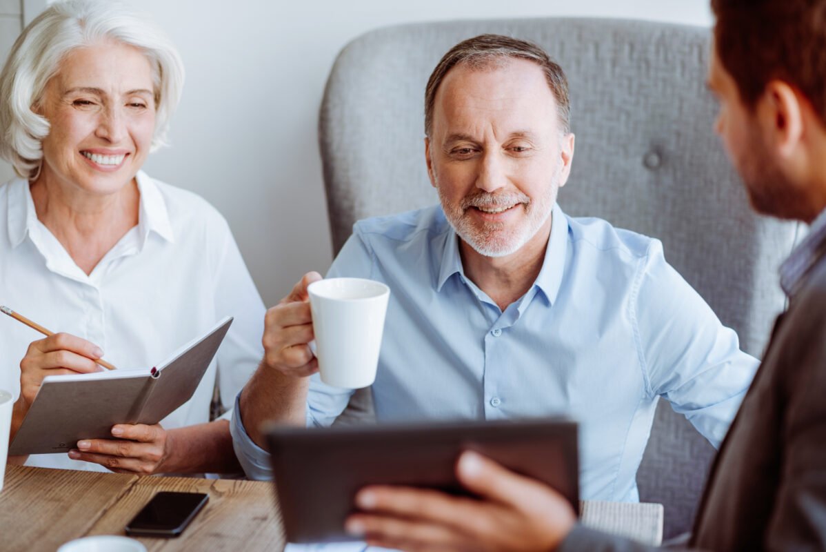 Life Settlements: Smiling aged couple meeting with life settlement broker