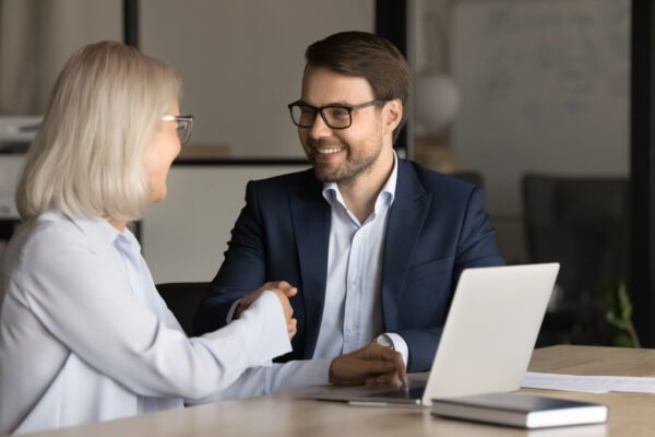 Life Settlement Broker: Positive successful professional shaking hands with senior woman
