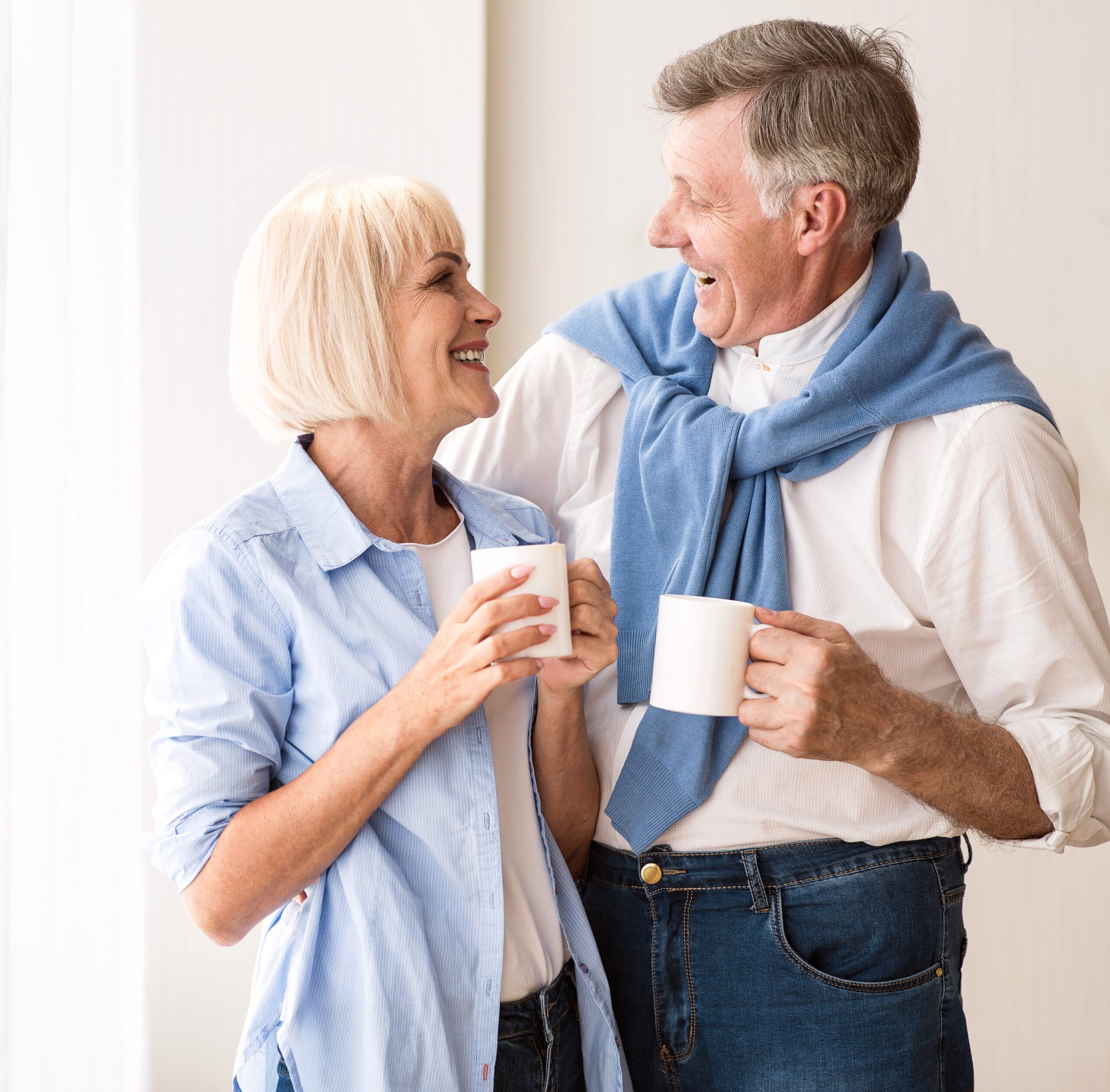 Best Company to Sell Your Life Insurance Policy: Happy senior couple talking near window and drinking tea